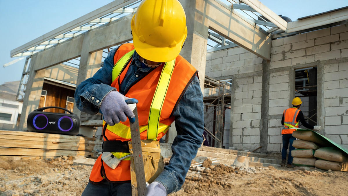 Construction worker on a building site with a portable speaker playing music in the background while working